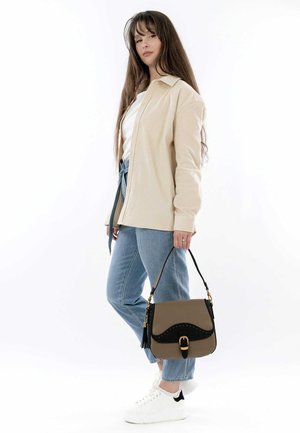 Beige corduroy jacket, white t-shirt, light denim jeans, and white sneakers. Brown and black handbag with gold hardware and tassel detail.