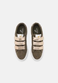Green suede sneakers featuring three metallic gold Velcro straps, white rubber sole, and a textured khaki lining with a printed pattern.