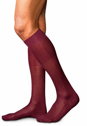 Calcetines burdeos hasta la rodilla con textura acanalada, acabado suave y un sutil brillo, diseñados para ofrecer cobertura y comodidad.