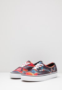 Sneakers in tela con un motivo ondulato multicolore in rosso, arancione, blu e nero. Lacci bianchi e suola in gomma con accenti neri.