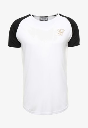 T-shirt blanc avec manches raglan courtes noires et petit logo de marque brodé en or sur le côté gauche de la poitrine.