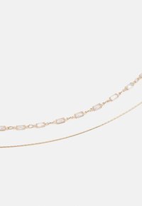 Collier en chaîne dorée avec des pierres précieuses rectangulaires et rondes alternées, doté d'un délicat design en maillons torsadés. Texture lisse, éclat subtil.