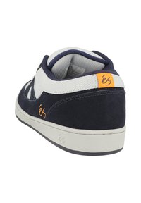 Námořnické modré semišové tenisky s bílými síťovinovými akcenty, s polstrovaným límcem boty a oranžovým štítkem s logem na zadní straně. Gumová podrážka.
