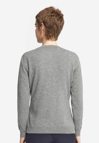 Szary sweter wykonany z miękkiego materiału, z okrągłym dekoltem, długimi rękawami oraz prostym wzorem z prążkowanymi mankietami i końcem.