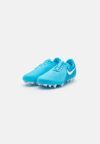 Scarpe da calcio Nike turchesi con tomaia testurizzata, logo swoosh bianco e tacchetti bianchi. Presentano una chiusura con lacci e un design aerodinamico.