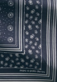 Granatowa tkanina z białym wzorem paisley i kwiatowym, obramowana paskami. U dołu znajduje się logo "marc o polo denim".