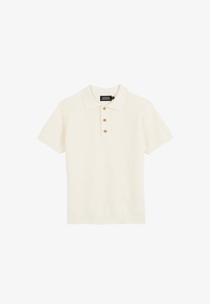 Polo en maille crème à manches courtes avec trois boutons en bois et un ourlet côtelé, posé à plat sur un fond blanc.