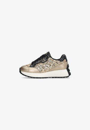 Schnürsportschuh in Schwarz und Gold. Merkmale ein funkelndes Obermaterial, metallische Akzente, gepolsterten Kragen und eine dicke weiße Sohle mit schwarzem Profil.