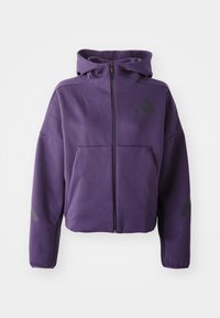 Purple zip-up hoodie with a high collar, featuring front pockets and black diagonal accents on sleeves and sides. Soft, textured fabric.