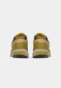 Baskets de course Nike avec une tige en mesh jaune, des accents gris et un design texturé. Semelle épaisse avec un bon amorti, détails de semelle extérieure noirs et jaunes.