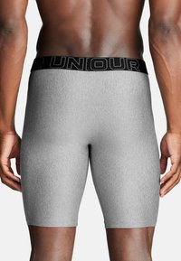 Graue Stretchshorts mit einem schwarzen strukturierten Bund. Der Stoff wirkt glatt und enganliegend, entworfen, um den Körper zu umschmeicheln.