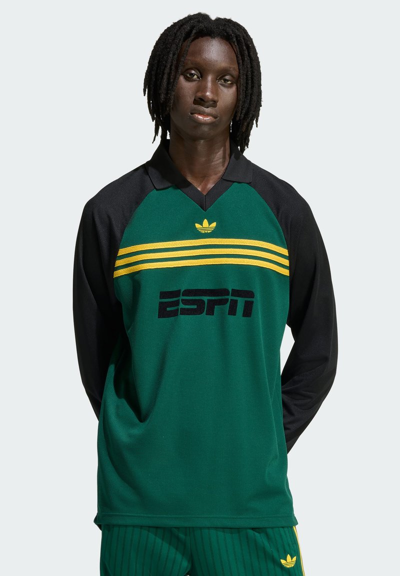 Zelena sportska majica s dugim rukavima, crnim rukavima, žutim prugama i logotipom ESPN-a. Ima ovratnik i tkaninu s teksturom.