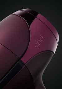 Haarföhn met een diepe bordeauxglanzende afwerking, gladde lijnen en een minimalistisch ontwerp; heeft het merklogo in subtiele verheven details.