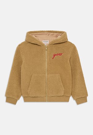 Brūns šerpa ar rāvējslēdzēju, kapuce, divas priekšējās kabatas, ribotie aproces un sarkans izšūts "guess" logo uz krūtīm.