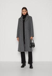 Grå ullfrakk med notched krage, frontlommer og seks knapper. Kombinert med svart turtleneck, bukser og hælboots.