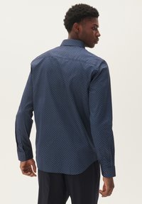 Camisa azul marino con patrón geométrico, de mangas largas y puños abotonados. Textura suave y diseño de cuello clásico.