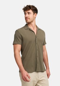 Korte mouwen knoopshirt in olijfgroen, gemaakt van een gestructureerde stof, met een losse pasvorm en een gekartelde kraag, met knopen aan de voorkant.
