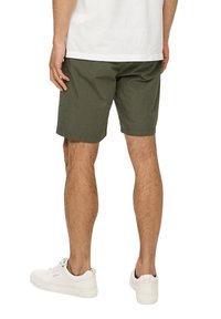 Olijfgroene katoenen shorts voor heren met een rechte snit, vijf zakken en omgeslagen zoom, gecombineerd met witte sneakers en een effen wit T-shirt.