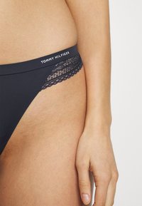 Mørkeblå truse med blonde detaljer på siden og en merket midje. Har en jevn tekstur og et elegant design for komfort.