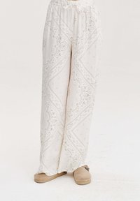 Bílé, vzorované kalhoty volného střihu s elastickým pasem. Ozdobené jemnými paisley vzory a z měkké, lehké tkaniny.