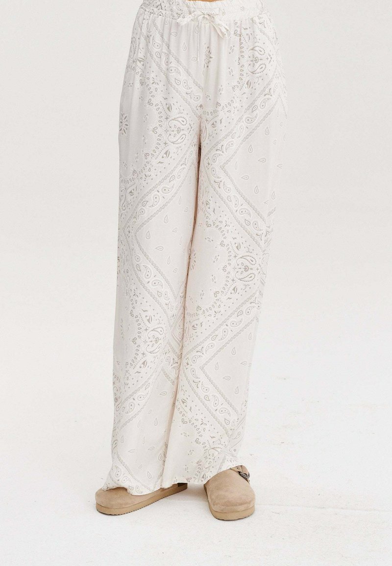Bílé, vzorované kalhoty volného střihu s elastickým pasem. Ozdobené jemnými paisley vzory a z měkké, lehké tkaniny.