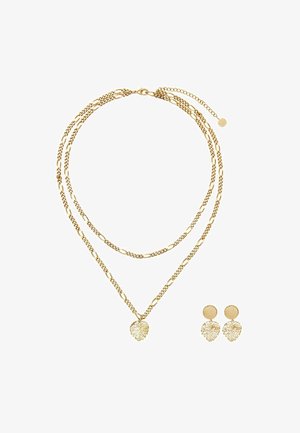 Naszyjnik w złotym odcieniu z warstwowanymi łańcuszkami i zawieszką w kształcie liścia; pasujące kolczyki o wzorze liścia. Gładka tekstura z błyszczącym wykończeniem.