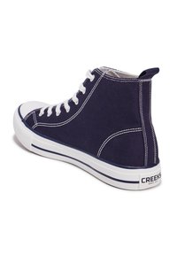 Sneaker alta in tela blu con lacci bianchi e suola in gomma. Presenta cuciture bianche e logo sul tallone.