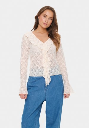 Spitzenbluse mit V-Ausschnitt, gerafftem Vorderteil, langen Ärmeln und ausgestellten Ärmeln in Cremefarbe. Filigranes florales Muster auf der gesamten Bluse.