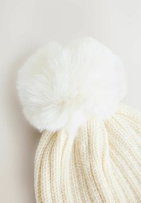 Bonnet tricoté blanc avec un grand pompon en fausse fourrure blanche et duveteux. Présente une texture côtelée et une forme arrondie. Matériau doux.