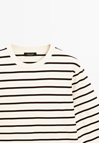 Gestreiftes Langarm-T-Shirt aus einem cremefarbenen Stoff mit dunkelbrown horizontalen Streifen, Rundhalsausschnitt und weichem Baumwollmaterial.