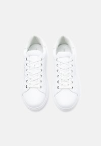 White leather sneakers featuring a round toe, flat laces, metal eyelets, and minimalistic design with no visible branding or patterns.
