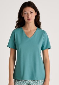 Turkoois korte mouwen t-shirt met een V-hals ontwerp. Soepele textuur met een ontspannen pasvorm, gecombineerd met gestreepte bloemen pyjamashorts.