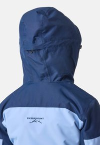 Marineblauwe en lichtblauwe waterdichte jas met een capuchon. Kenmerkt zich door een logo op de achterkant en een zachte textuur, ontworpen voor buitengebruik.