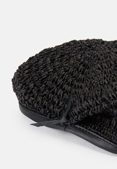 Chapeau de paille noir avec un motif tissé texturé, doté d'une finition en cuir noir lisse et d'un détail noué sur le côté.