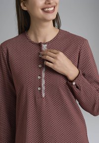 Blusa a fantasia marrone con scollatura rotonda, bordino in pizzo e cinque bottoni. Maniche lunghe con polsini a bottone; tessuto morbido.