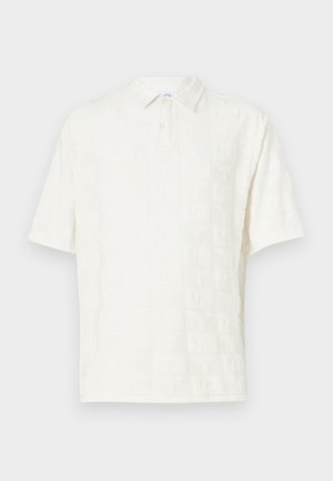 Hvit kortermet polo skjorte med teksturerte mønstrede blokker overalt, med krage og knappestolpe for lukking.