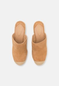 Tan mockasiner i mocka med en texturerad jute-sula. Har öppen häl och rund tå. Mjuk lädersula med präglad logotyp.