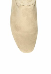 Chaussure beige en daim à bout pointu avec une texture lisse et un design minimaliste. Elle présente une tige basse et aucun détail de quincaillerie visible.