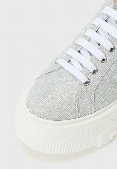 Silver canvas sneaker with a textured finish, white laces, and a thick white rubber sole. Features round eyelets and a rounded toe.