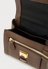 Pruun nahast käekott, krobeline tekstuur, kuldsed riistvaradetaile, tõmblukuga tasku ja musta kangaga vooder. Brändi logo nähtav.