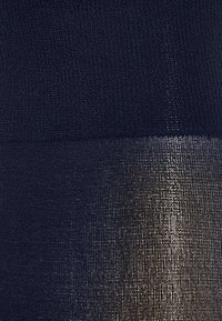 Marineblå tekstureret stof med en gradient, der overgår til en skinnende metallisk finish, der viser kontrasterende materialer og farver.