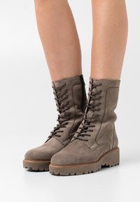 Braune Wildleder-Stiefeletten mit Schnürvorderseite, seitlichem Reißverschluss und strukturiertem Gummisohle. Verfügen über eine klobige Plateausohle und Nahtdetails.