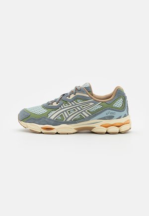 Løbesko med blå, grøn og beige mesh og ruskindsoverdel, beige polstret sål og side- og hældetaljer med mærke.