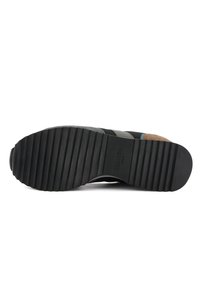 Suola di scarpa in gomma nera con texture rigata, bordi lisci e impronta del logo. Il materiale passa dalla gomma a dettagli in suede.