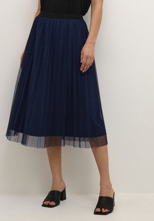 Gonna plissée blu navy con una finitura trasparente e testurizzata e una vita elastica nera. Indossata con sandali con tacco a blocco aperti davanti neri.
