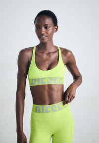 Neon grön sport-bh och leggings med grå "DIESEL"-tryck. Tyget är slätt med en åtsittande design, med breda band och hög midja.