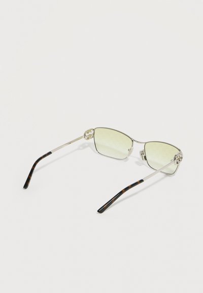 Λεπτά γυαλιά ηλίου με μεταλλικό σκελετό, με φακούς ελαφρώς κιτρινωπούς και ακρολήψεις βάσης σε μοτίβο καβούκι χελώνας, πάνω σε λευκή επιφάνεια.