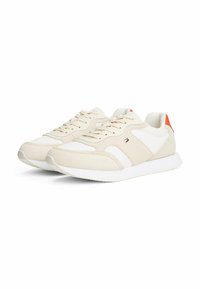Sneaker beige con dettagli in pelle bianca, camoscio testurizzato e suola in gomma bianca. Dotate di lacci e una piccola linguetta arancione sul tallone.