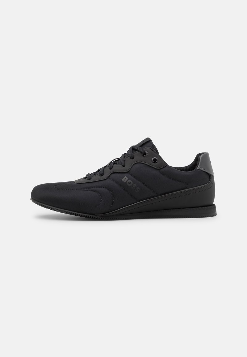 Sorte sneakers med en glat tekstiloverdel, snørebåndsdesign, teksturerede overlejringer og en slank, kontureret sål med diskret branding.