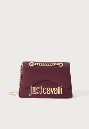 Petit sac à main bordeaux avec bandoulière en chaîne dorée et grand logo doré "Just Cavalli" sur le rabat avant, sur fond uni.